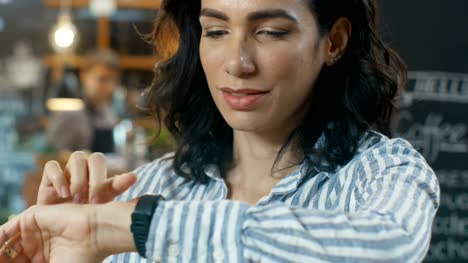 Beautiful-Woman-Checking-Messages-on-Her-Smartwatch.-She's-in-the-Modern-Looking-Coffee-Shop.