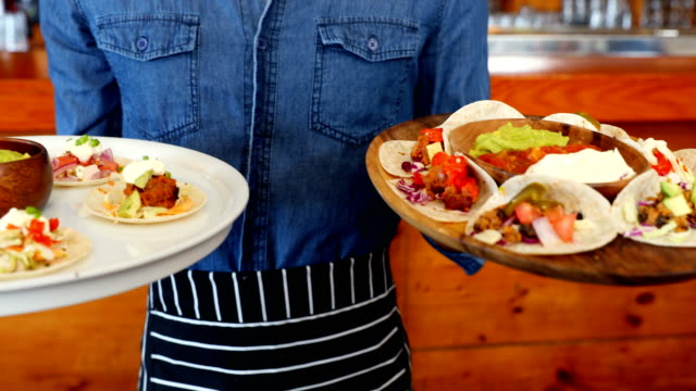 Waiter-holding-plate-of-mexican-food-in-bar-4k
