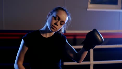 Beautiful-kickboxing-woman-adjusting-boxing-gloves-and-wiping-sweat-in-the-gym.