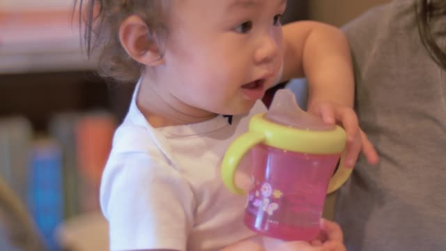 Ein-Kleinkind,-statt-sich-von-ihrer-Mutter-trinkt-aus-ihrer-sippy-Tasse
