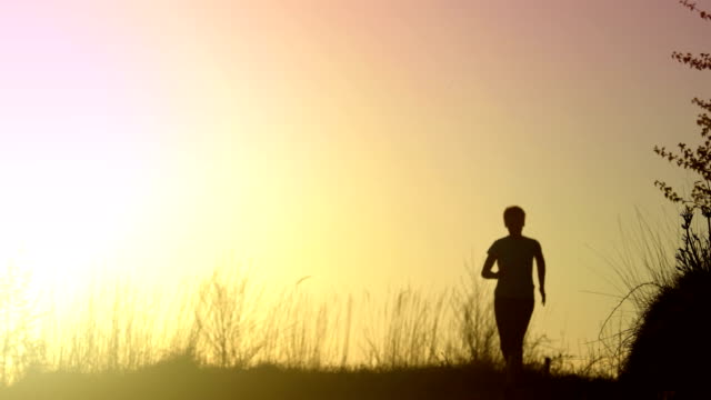 Young-athletic-woman-is-running-outdoor-at-sunset-in-mountain-landscape.