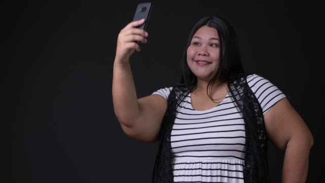 Schöne-Übergewicht-asiatische-Frau-mit-Handy-auf-schwarzem-Hintergrund