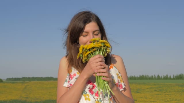 Retrato-de-mujer-en-campo-con-ramo-de-flores-de-diente-de-León-amarillas-lo-olfateando-a