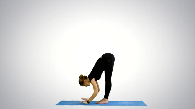 Young-woman-doing-yogic-sun-salutation-pose-on-mat-on-white-background