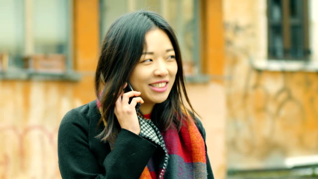 sonriente-mujer-bastante-China-hablando-por-teléfono-en-el-street