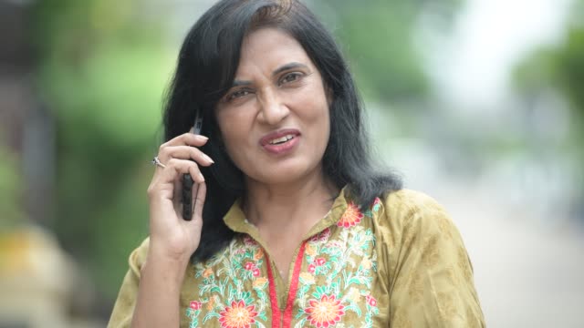 Madura-hermosa-mujer-India-hablando-por-teléfono-en-el-exterior-de-las-calles