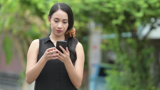 Junge-schöne-asiatische-geschäftsfrau-mit-Telefon-in-den-Straßen-im-freien