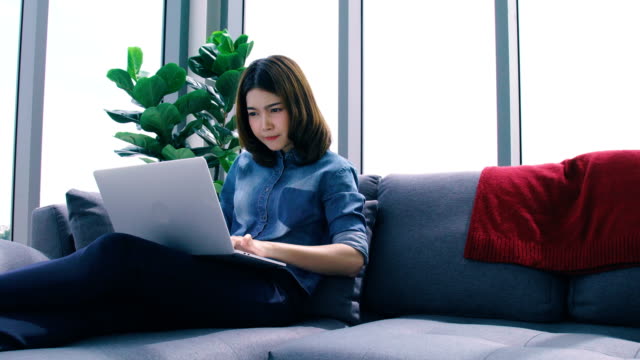 schöne-intelligente-asiatische-Frau-entspannen-Zeit-mit-Online-Shop-Laptop-im-Wohnzimmer-Haus-Hintergrund