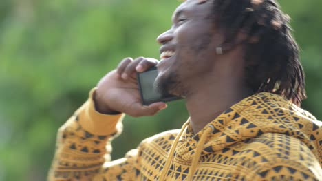 Young-happy-handsome-African-man-smiling-while-calling-in-the-streets-outdoors