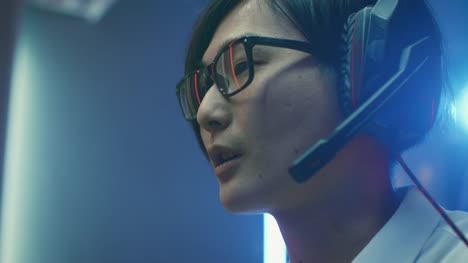 Close-up-Portrait-of-the-Professional-Gamer-Playing-in-Online-Video-Game,-He's-wearing-Glasses,-talks/-chats-with-His-Teammates-/-Friends-through-Headphones.-Neon-Colored-Room.-eSport-Cyber-Games-Internet-Championship-Event.