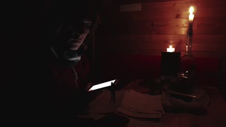 Woman-using-smartphone-hand-writing-paper,-candle-light-in-dark-room