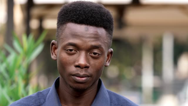 nachdenklicher-jungen-afrikanischer-Mann-anfängt-zu-lachen-in-die-Kamera