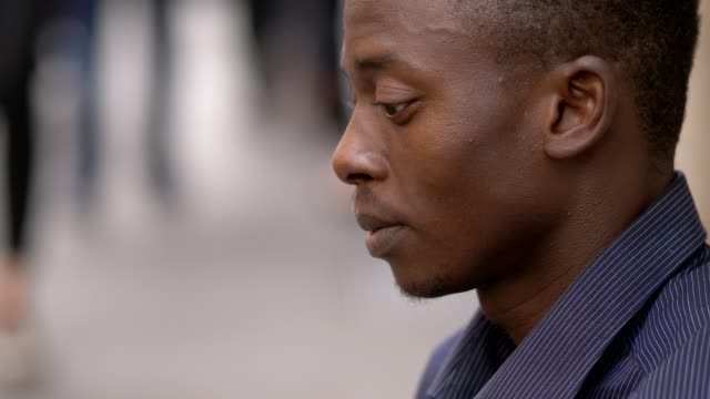 Depressiv-traurig-einsam-junger-schwarzer-afrikanischer-Mann-in-das-Profil-der-Stadt