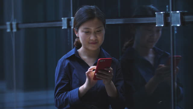 Junge-asiatische-geschäftsfrau-mit-Handy-stützte-sich-das-Office-Fenster,-4k