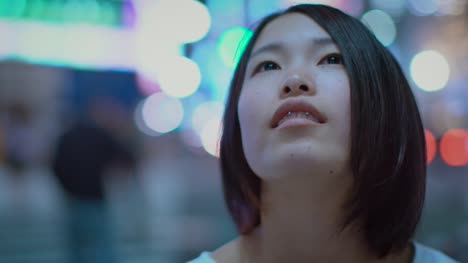 Porträt-von-die-attraktive-Japanerin-mit-Piercing-und-Casual-tragen-sieht-um-sie-herum-in-Staunen.-Im-Hintergrund-Plakate-Großstadt-Werbung-Lichter-leuchten-in-der-Nacht.