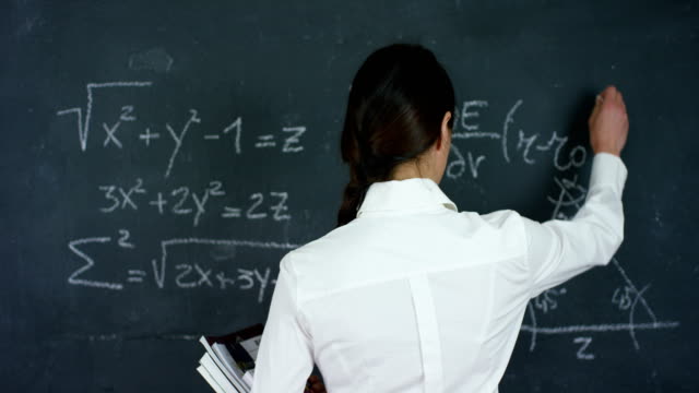 Portrait-of-a-beautiful-girl,-teacher-or-student-solves-examples,-formulas,-triangle-on-a-black-board,-on-a-black-background.