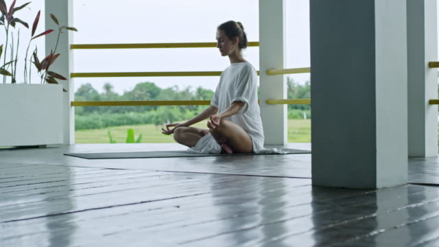Mujer-meditando-cuando-sentado-en-la-estera-de-la-Yoga