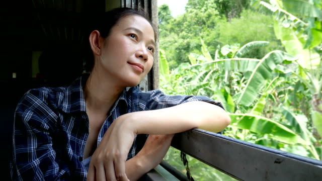 Imágenes-de-4K-de-mujer-asiática-viaje-en-tren-mirando-por-la-ventana-del-tren-en-ferrocarril-tren-Inicio-en-Bangkok-ir-a-Kanchanaburi-en-Tailandia.-disfrutar-de-transporte-por-tren-vintage