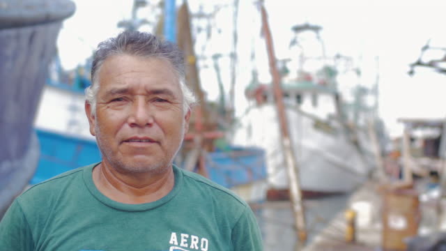 Close-up-portrait-of-an-older-man-of-hispanic-heritage-standing-in-front-of-a-boatyard-in-Mexico