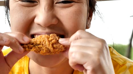 Süße-Asiatin-Nahaufnahme-freuen-uns-gebratene-Hähnchenschenkel-im-Restaurant-zu-essen.-4k-Video-Zeitlupe