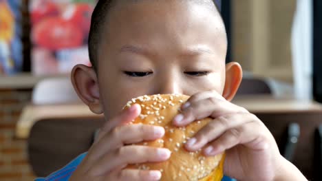 Nahaufnahme-junge-Asiaten-essen-Burger,-niedlich-fröhlicher-junge-Hamburger-Restaurant-halten.-Video-Zeitlupe
