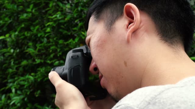 Rear-side-view-of-young-male-photographer-taking-photos-in-nature-scenery