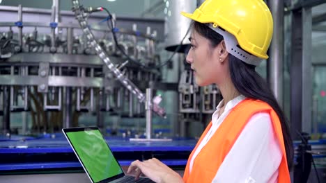 Woman-industrial-engineer-at-work-in-factory.-Beautiful-young-chinese-engineer-working-in-large-factory.-With-safety-helmet-and-jacket.-High-tech-automatic-machine-in-background.