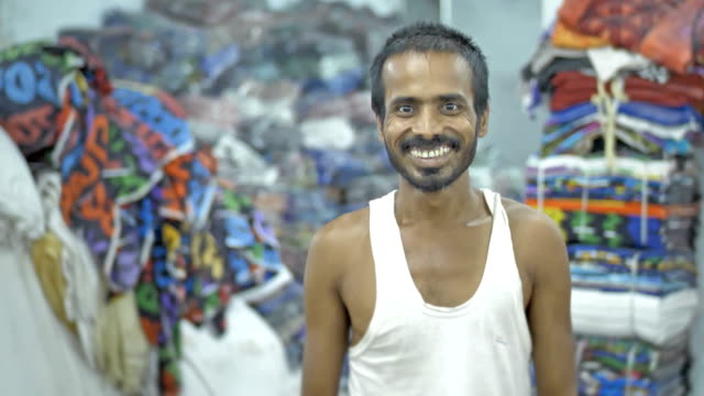 Ein-glücklicher-Mensch-oder-Hilfsarbeiter-in-der-Kamera-mit-einem-Lächeln-in-einem-Textil-Werkstatt-suchen