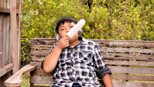 Süße-asiatische-Kinder-Eis-essen-und-hören-Sie-Musik-im-park