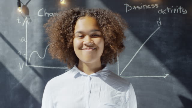 Black-Businesswoman-Standing-at-Chalkboard-and-Smiling