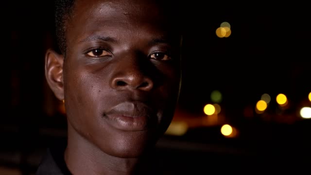 Sad-young-black-african-migrant-staring-at-camera-in-the-night--outdoor