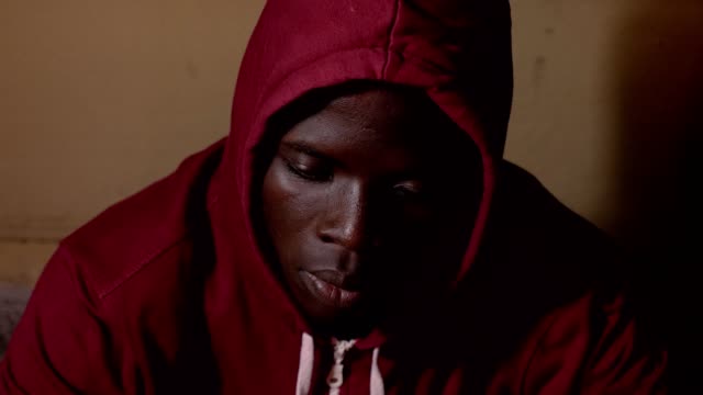 Traurig-stolz-einsamer-junger-Kapuzen-afrikanischen-Mann-allein-im-Dunkeln,-starrte-auf-Kamera