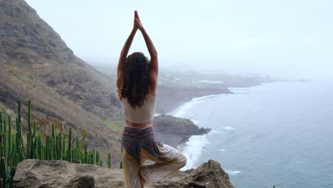 Mujer-meditando-en-pose-de-yoga-Guerrero-en-las-montañas-al-mar,-playa-y-roca.-Motivación-e-inspiración-para-montar-y-ejercicio.-Estilo-de-vida-saludable-al-aire-libre-en-la-naturaleza,-concepto-de-fitness.