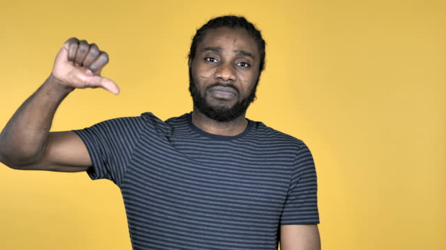 Casual-African-Man-Gesturing-Thumbs-Down-Isolated-on-Yellow-Background