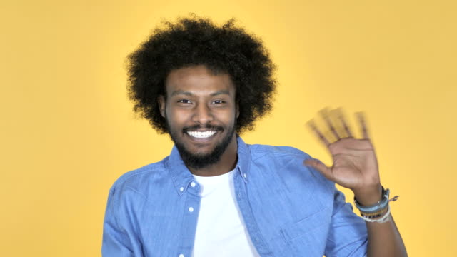 Hombre-afroamericano-saludando-de-mano-a-recepción-sobre-fondo-amarillo