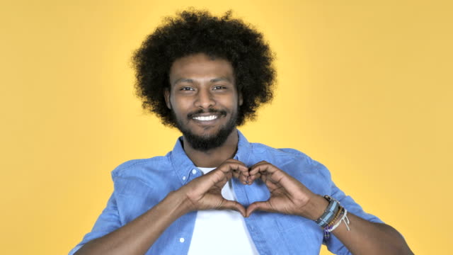 Handgefertigte-Herzen-von-afroamerikanischen-Mann-auf-gelbem-Hintergrund
