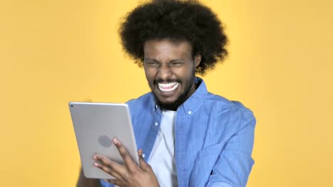 Hombre-afroamericano-emocionado-de-éxito-mientras-que-usando-la-tableta-sobre-fondo-amarillo