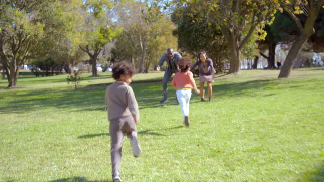 Happy-kids-running-to-Interracial-parents-in-park