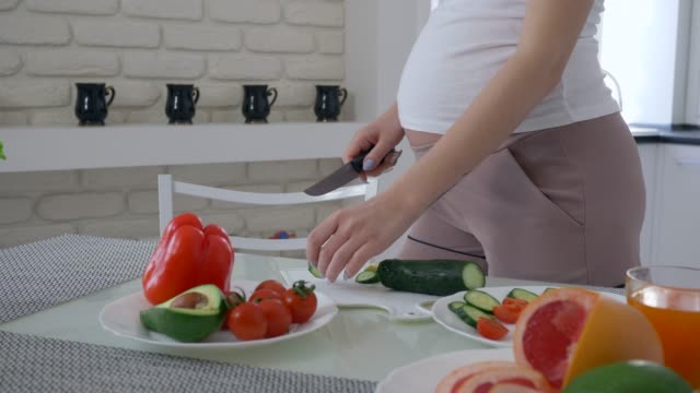 gesunde-Zukunft-Mutter-mit-dicken-Bauch-ist-nützlich-leckeren-Salat-aus-frischem-Gemüse-zur-Mittagszeit-Küche-kochen