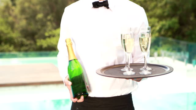 Smiling-waiter-holding-champagne-bottle-and-flute