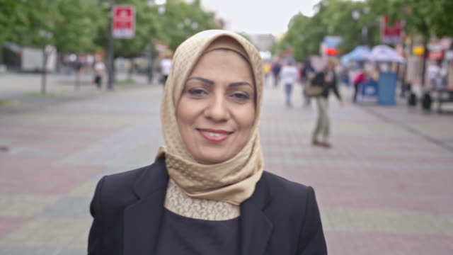 Zuversichtliche-mittlere-erwachsene-arabische-Frau-zu-Fuß-die-Straße