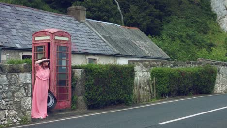 4k-Shot-of-a-Woman-posing-in-a-Red-Telephone-Box,-United-Kingdom