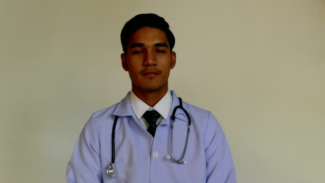 Handsome-medical-doctor-with-a-stethoscope-around-his-neck-is-looking-and-smiling-at-camera-while-standing-with-folded-arms