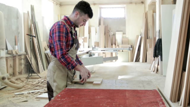 4K-un-hombre-joven-trabaja-en-la-producción-de-muebles.-Carpintero-o-manos-de-carpintero-trabajador-mediante-ruleta,-medir-algo-en-tablón-de-madera.