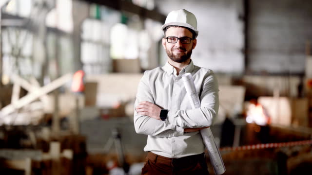 An-adult-architect-in-a-helmet-stands-at-the-current-construction-site,-in-his-hands-a-project-for-the-modernization-of-an-abandoned-factory-in-the-city