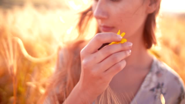 Mujer-joven-con-pie-de-flor-amarilla-en-un-campo-de-oro