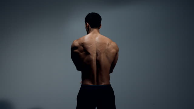 Männlichen-Fitness-Modell-zeigt-Rückenmuskulatur-durch-Dehnübungen-durchführen