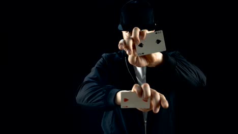 Professional-Street-Magician-in-a-Cap-Performs-Impressive-Sleight-of-Hand-Card-Trick.-Background-is-Black.