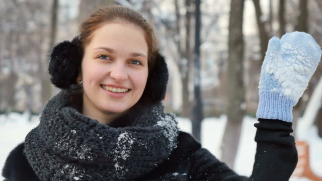 Hübsche-Dame-\"Wellenlinien\"-ihre-Hände-in-Handschuhe-an-der-Kamera-im-Winterpark-Hintergrund