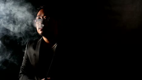 Kaufmann-im-schwarzen-Anzug-dampfen-elektronische-Zigarette-macht-Rauchwolken,-Mann-Rauchen-e-Zigarette,-Nikotin-süchtig